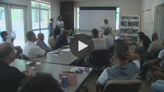 Video still of people gathered around a conference room table