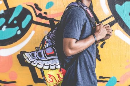 Student with backpack walking in front of a mural